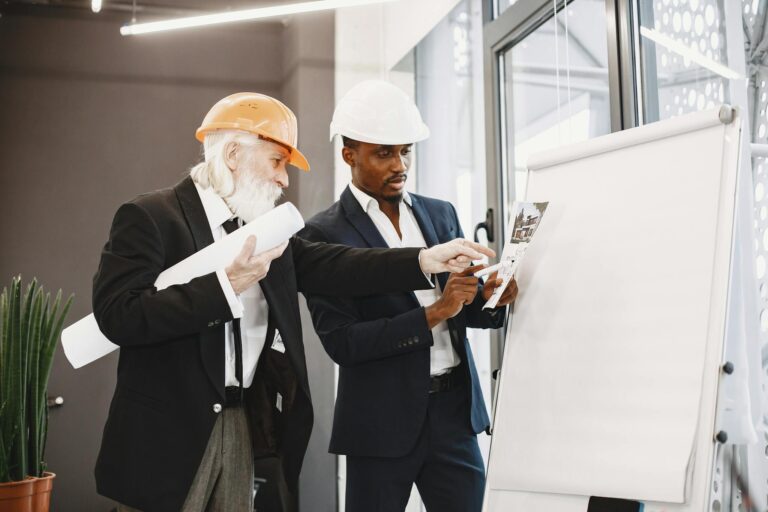 Two engineers discussing blueprints in an office setting.